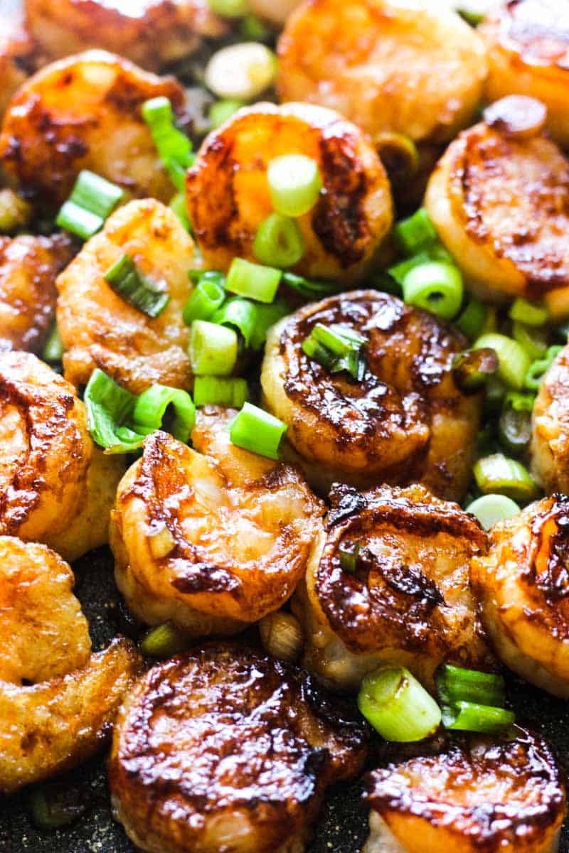 browned seafood in a pan covered with chopped green onions